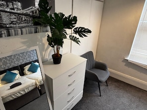 A bedroom with a bed, a dresser, a chair, and a potted plant. - Derby Home Stay, Sleeps 4, Near City Centre (Derby)