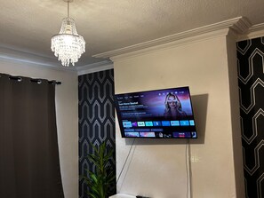 A television mounted on a wall displaying a streaming service interface with a selection of shows. - Derby Home Stay, Sleeps 4, Near City Centre (Derby)