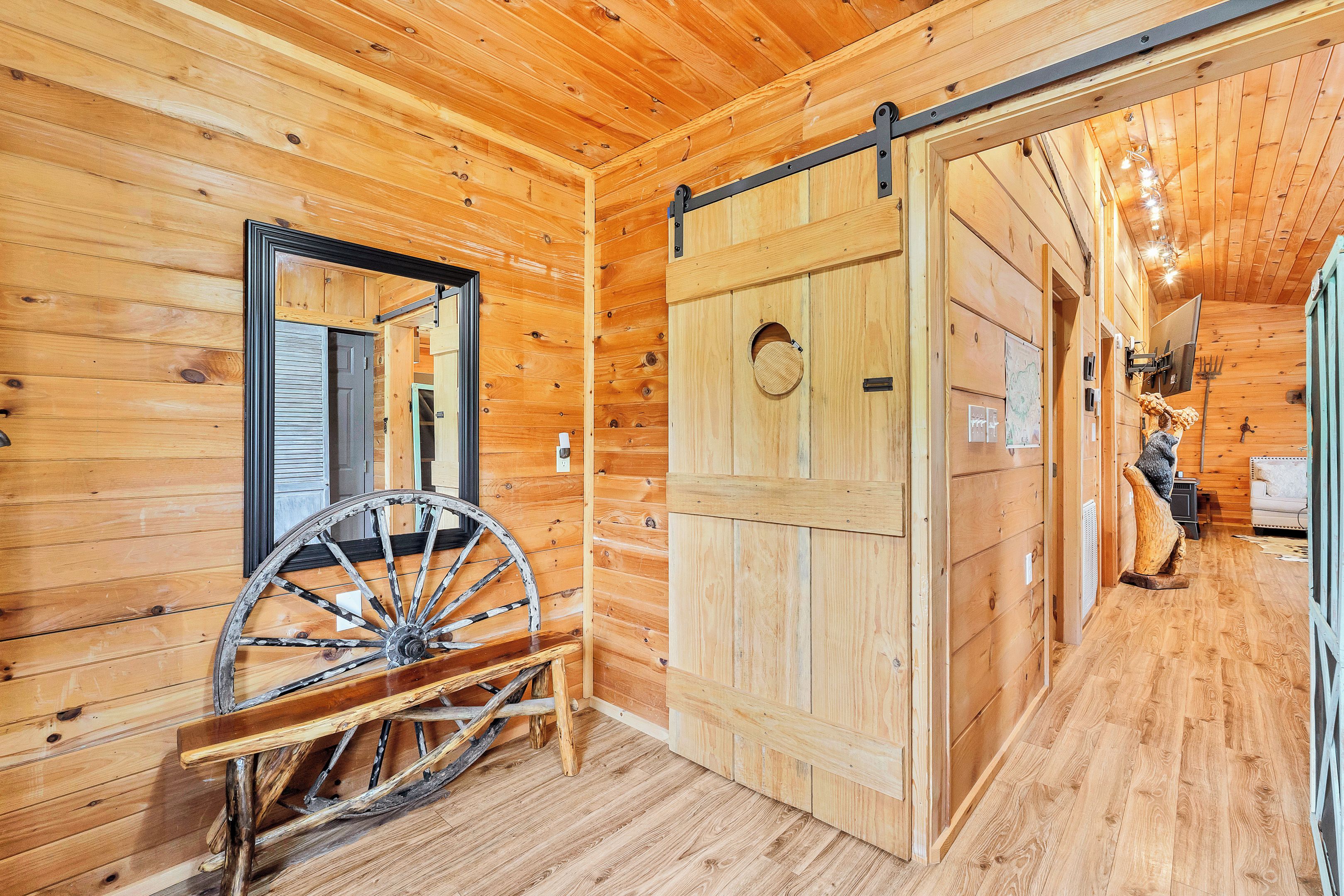 A wooden interior with a large wooden wheel, a sliding barn door, and a mirror on the wall.