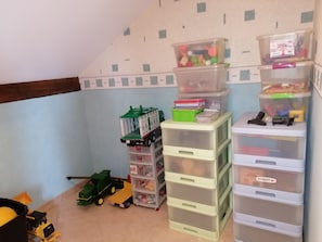 A storage area with multiple plastic drawers and a toy tractor. - Tortue Accommodation - shared kitchen (Rainville)