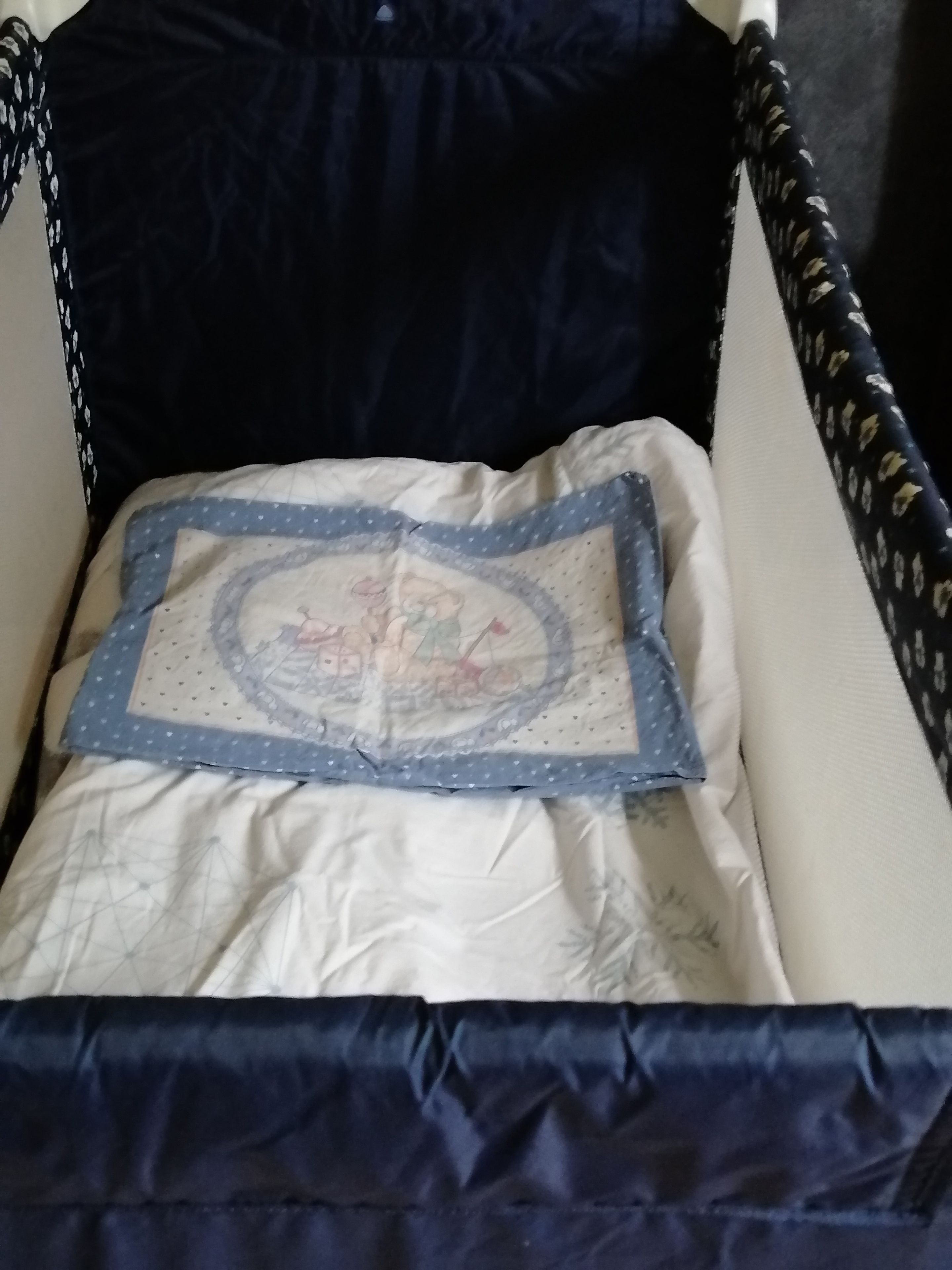 Un berceau avec une tête de lit bleu foncé et un oreiller matelassé orné d’un motif géométrique.