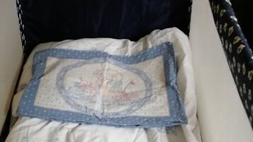 Un berceau avec une tête de lit bleu foncé et un oreiller matelassé orné d’un motif géométrique.