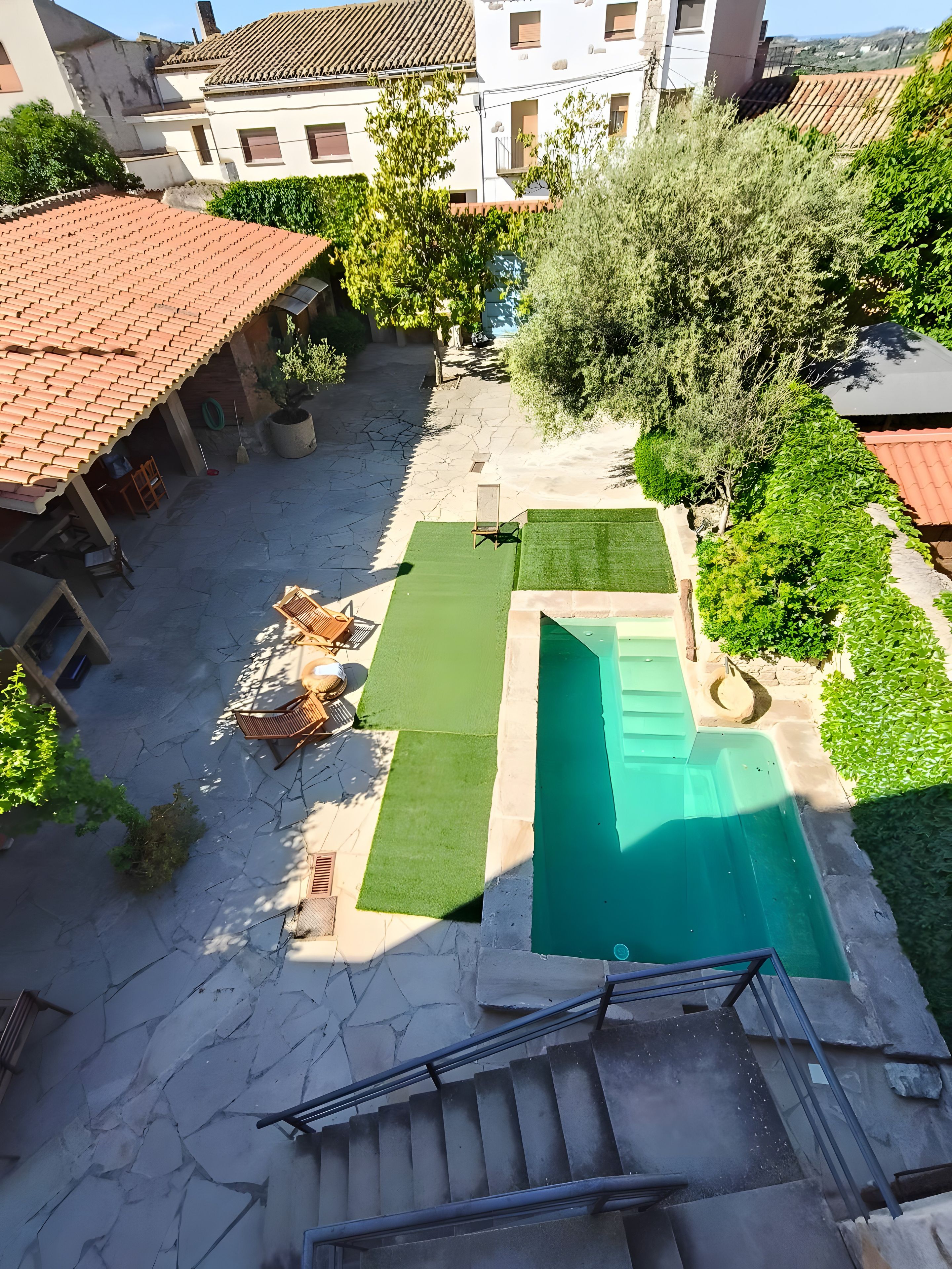 Une cour avec une piscine, une petite pelouse et un escalier menant à un bâtiment.