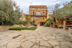 Un pati amb paviment de pedra, una escala que condueix a un segon pis i una zona de menjador amb seients exteriors.