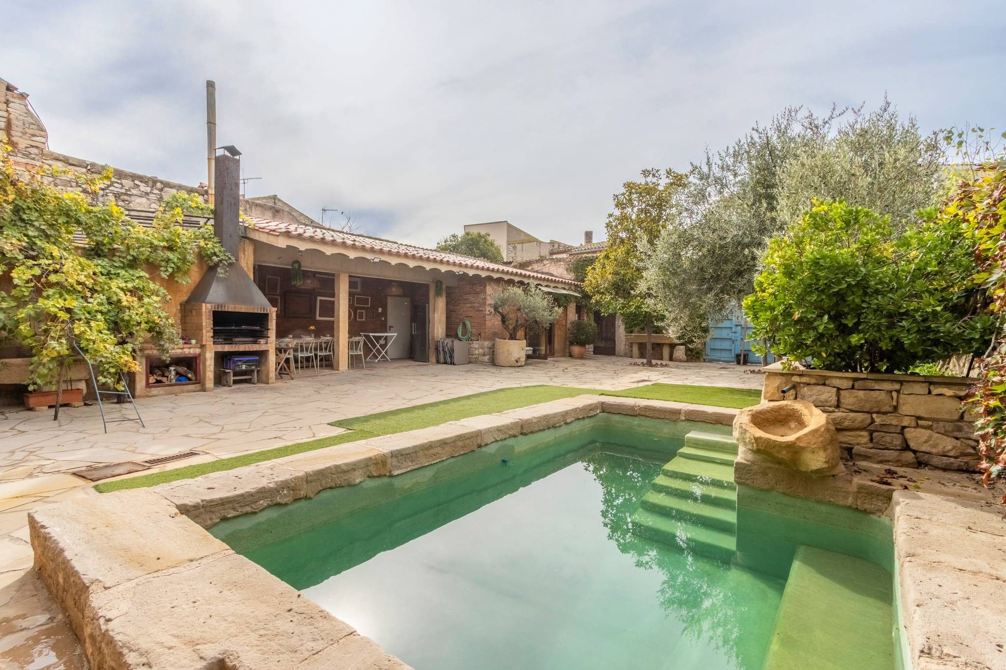 Un patio con piscina, mobiliario exterior y zona de barbacoa.