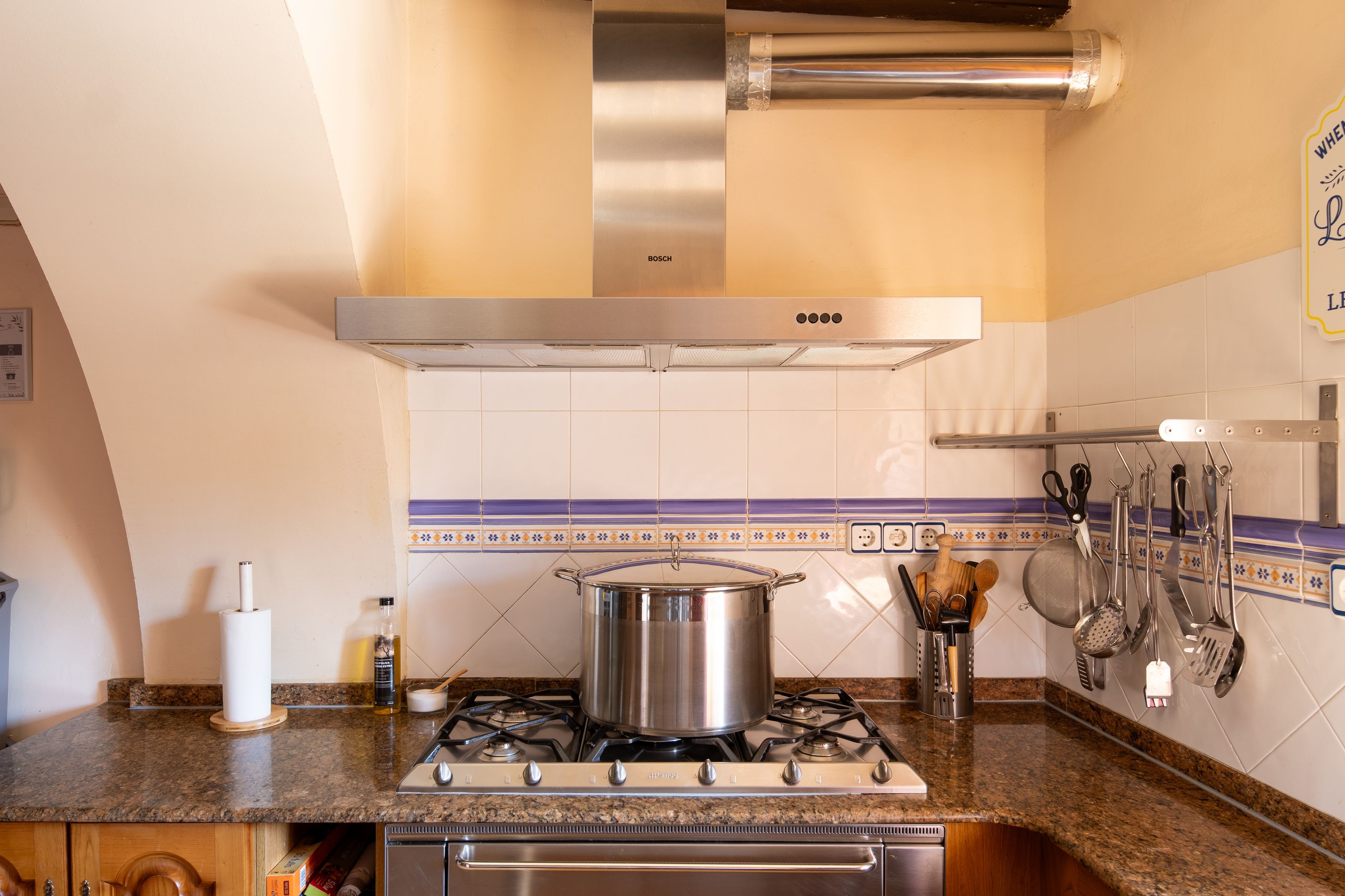 A kitchen with a stove, a pot, and various utensils.