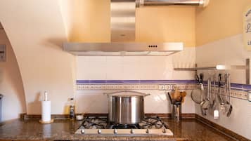 A kitchen with a stove, a pot, and various utensils.