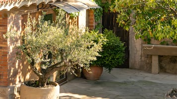 A courtyard with a tiled roof, potted plants, and a stone bench.