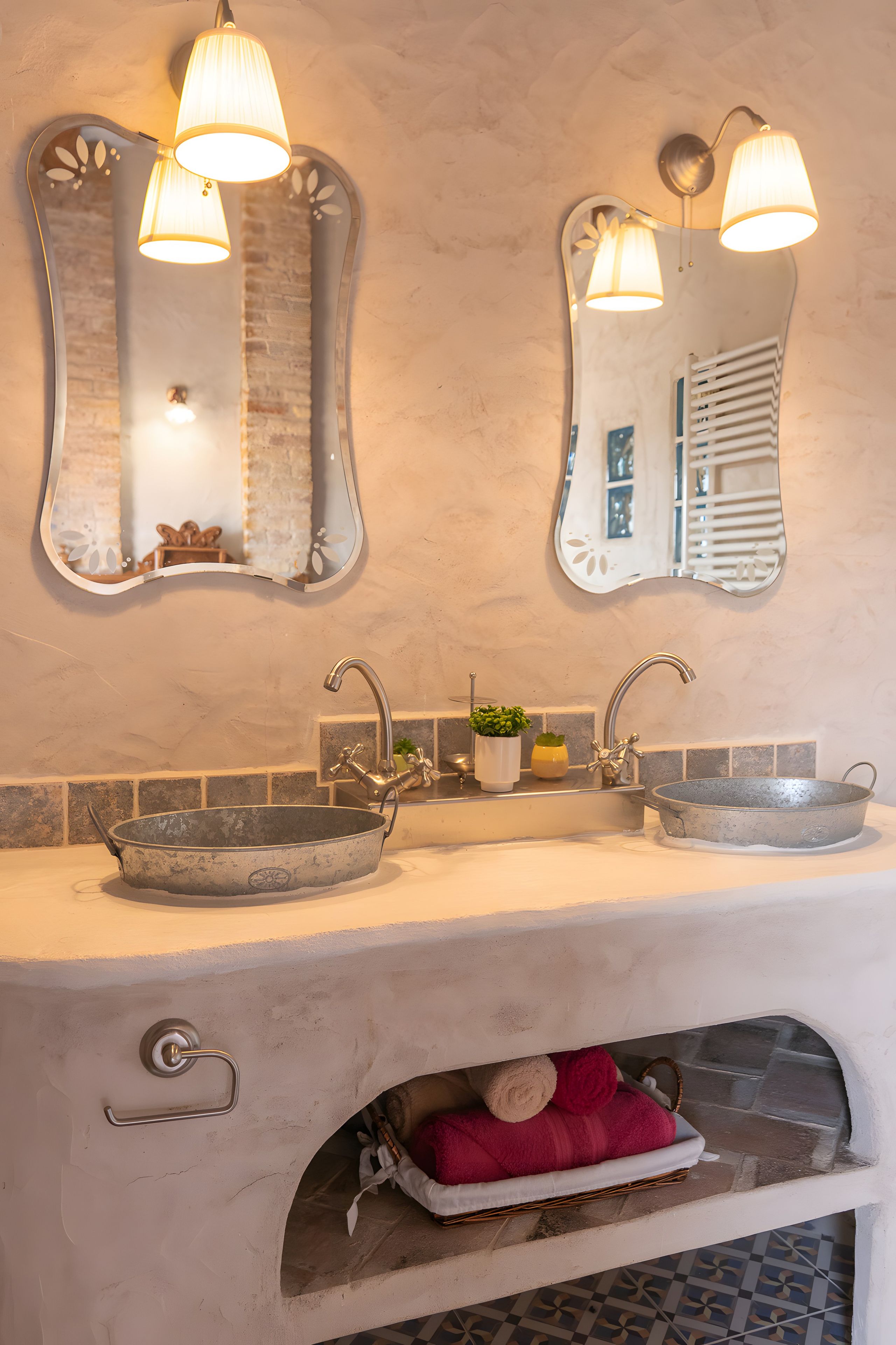 Baño con dos lavamanos, cada uno con un lavabo tipo recipiente, un espejo y un aplique de pared.