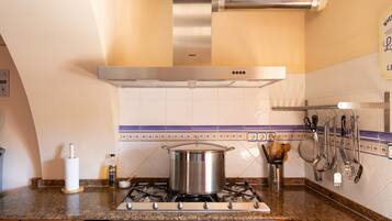 Una cocina con estufa, olla y varios utensilios.