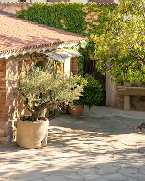 A courtyard with a tiled roof, potted plants, and a stone bench. - Room 'La Vinya' with Kitchen Access, Garden, Pool and Wi-Fi (Sant Martí de Maldà)