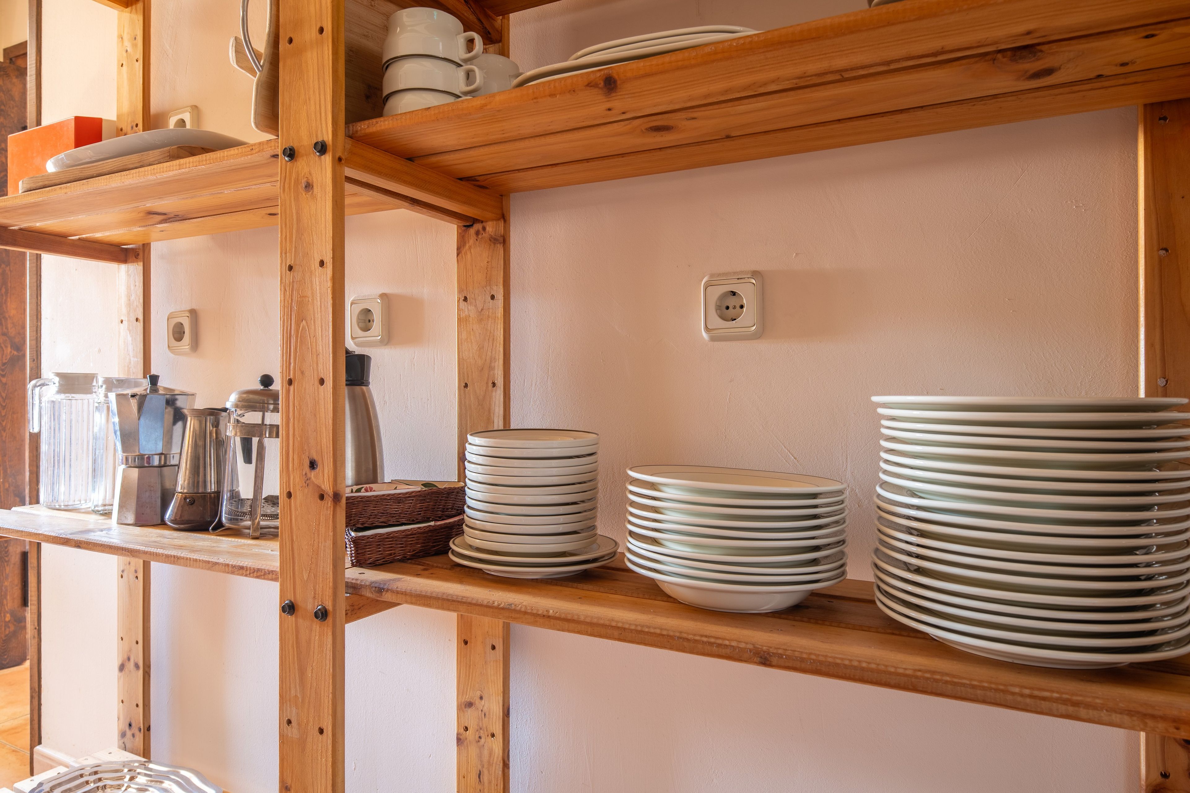 Une étagère de cuisine avec des assiettes empilées et une machine à café.