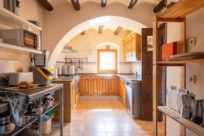 A kitchen with wooden cabinets, a central island, and a tiled backsplash. - Room 'La Vinya' with Kitchen Access, Garden, Pool and Wi-Fi (Sant Martí de Maldà)