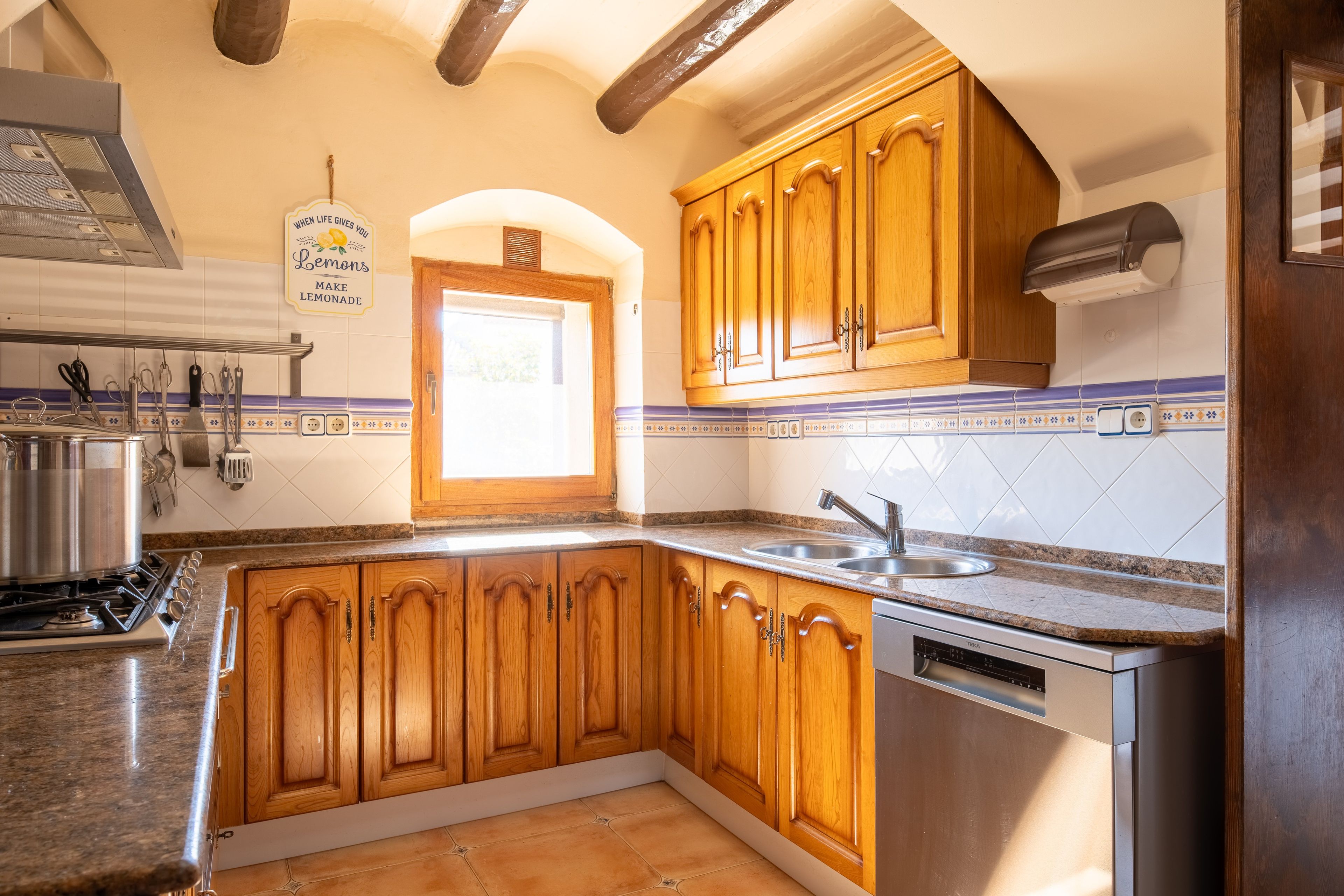 A kitchen with wooden cabinets, a stainless steel sink, and a built-in dishwasher.