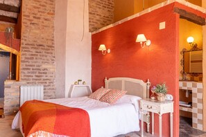 A bedroom with a bed, bedside table, lamp, and a red accent wall. - Room 'Presseguer' with Private Terrace, Kitchen Access, Garden, Pool and Wi-Fi (Sant Martí de Maldà)