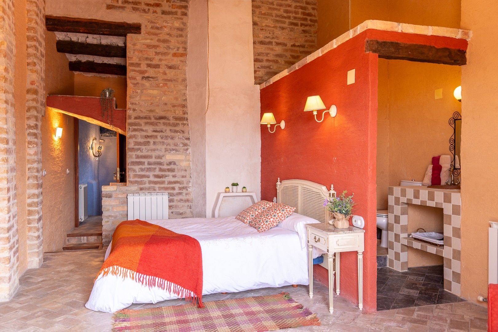 Une chambre à coucher avec un lit, une table de chevet, une lampe et une vue sur la salle de bain.