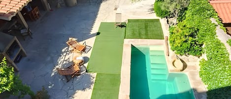 Une cour avec une piscine, une petite pelouse et un escalier menant à un bâtiment.