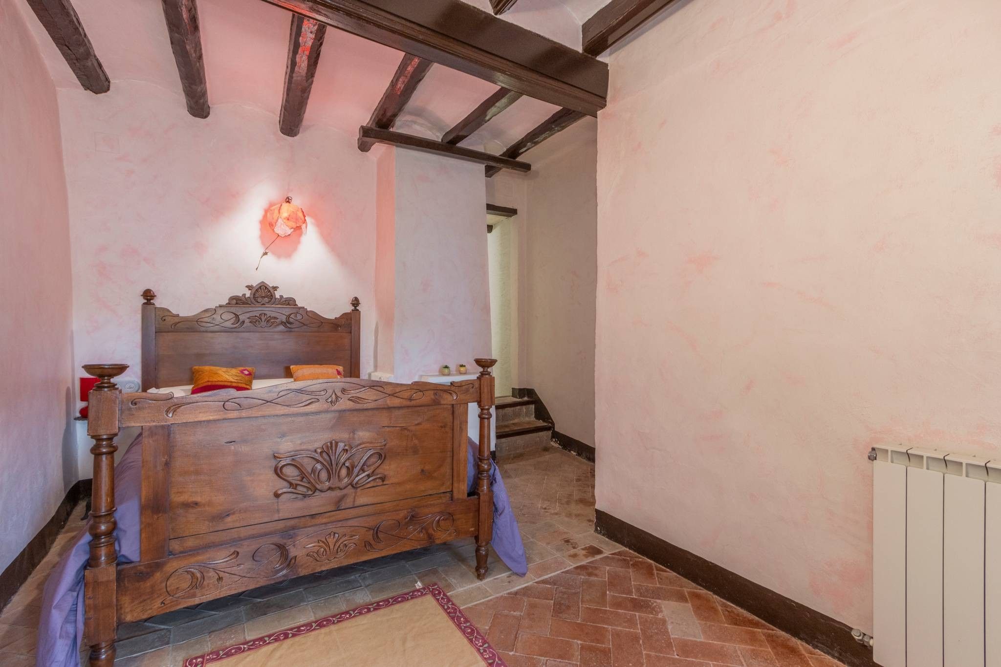 Un dormitorio con cama de madera, radiador y suelo de baldosas.