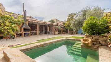 Un patio con piscina, mobiliario exterior y zona de barbacoa.