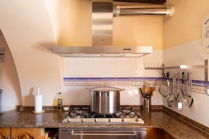 Una cocina con estufa, olla y varios utensilios.