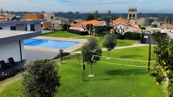 A residential area with a swimming pool, a tennis court, and a church in the background.