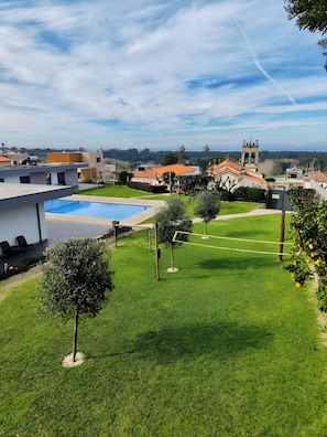 A residential area with a swimming pool, a tennis court, and a church in the background. - Tiny Home 'Casa Azul' with Sea View, Shared Pool and Wi-Fi (Cristelo)