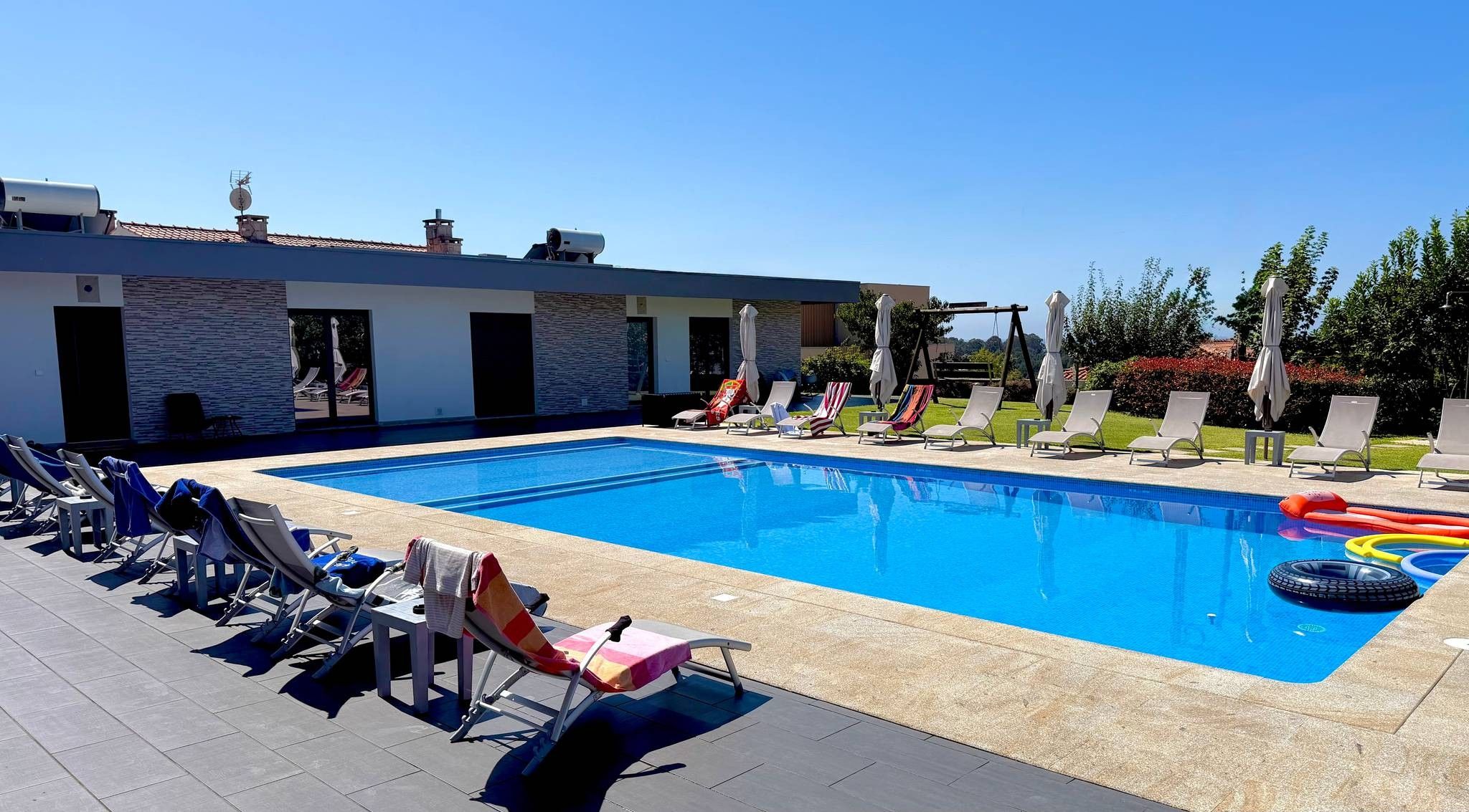 Ein Schwimmbecken mit Liegestühlen und Sonnenschirmen, umgeben von einem Gebäude mit steinernen Fassaden.