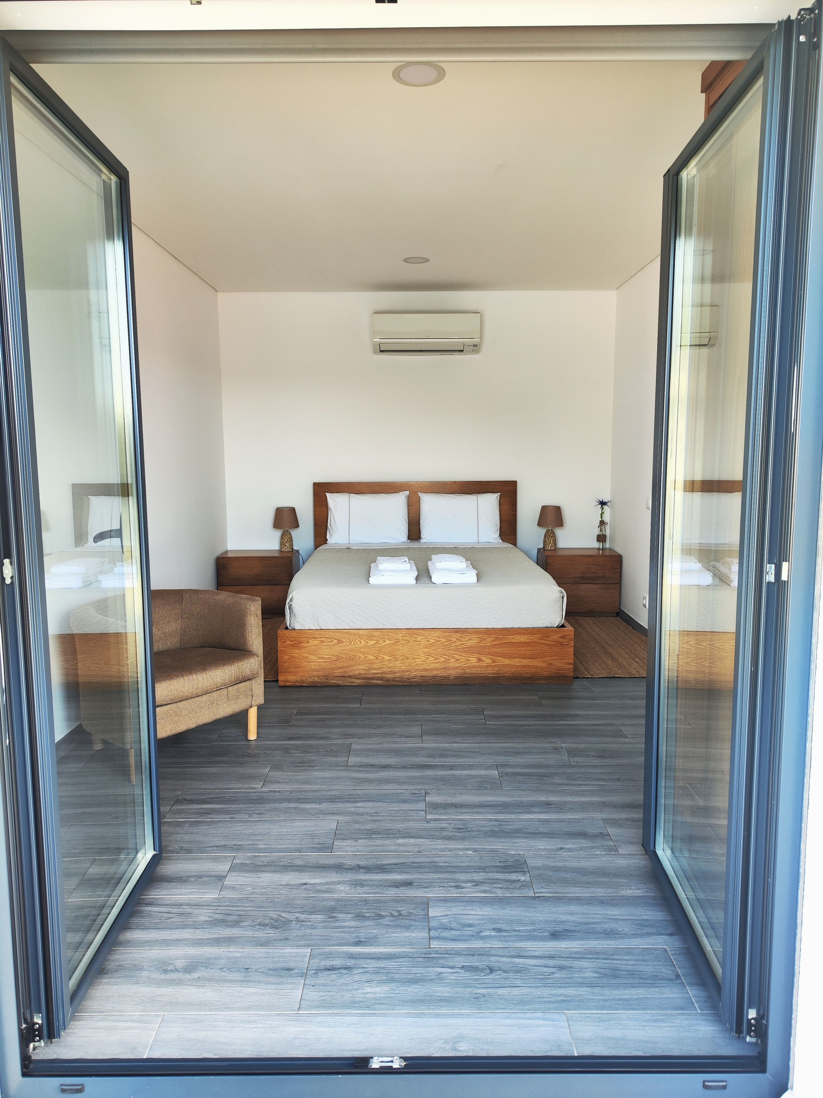 A bedroom with a bed, bedside tables, a chair, and a sliding glass door.