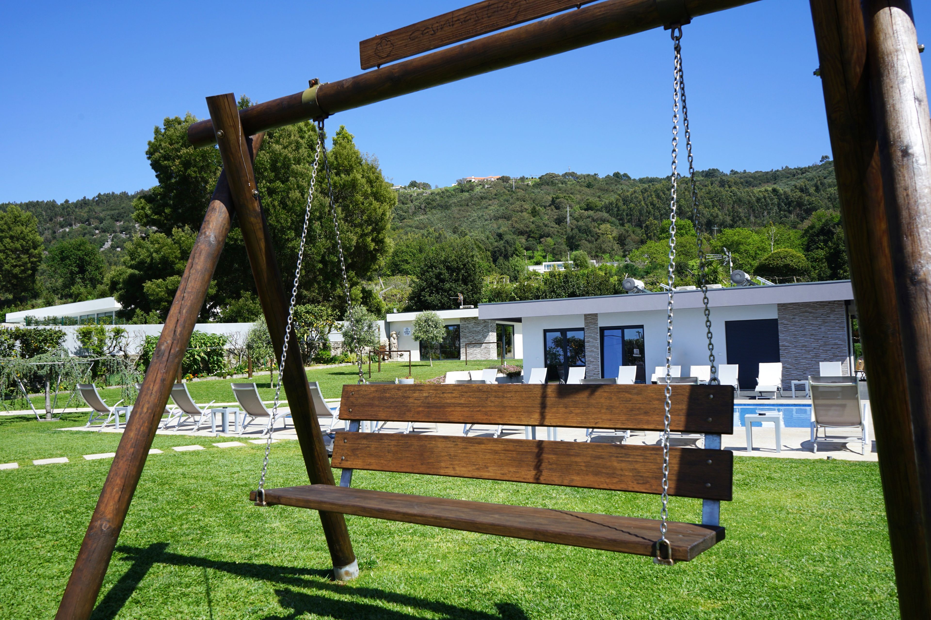 A wooden swing set in a grassy area with a modern building in the background.