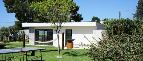 A modern house with a small garden, a hammock, and a ping pong table.