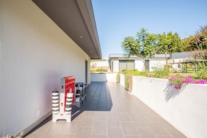 A modern outdoor area with a foosball table, a wall-mounted air conditioning unit, and a garden with flowers and shrubs. - Tiny Home 'Casa Amarela' with Sea View, Shared Pool and Wi-Fi (Cristelo)