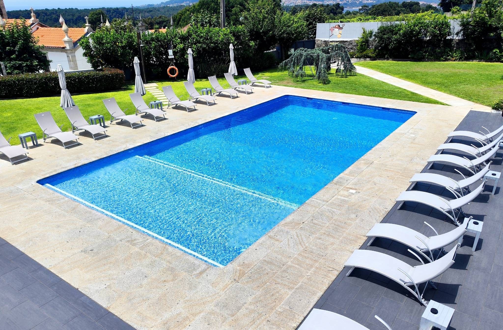 Ein rechteckiger Swimmingpool mit klar blauem Wasser, umgeben von einer gefliesten Liegefläche.