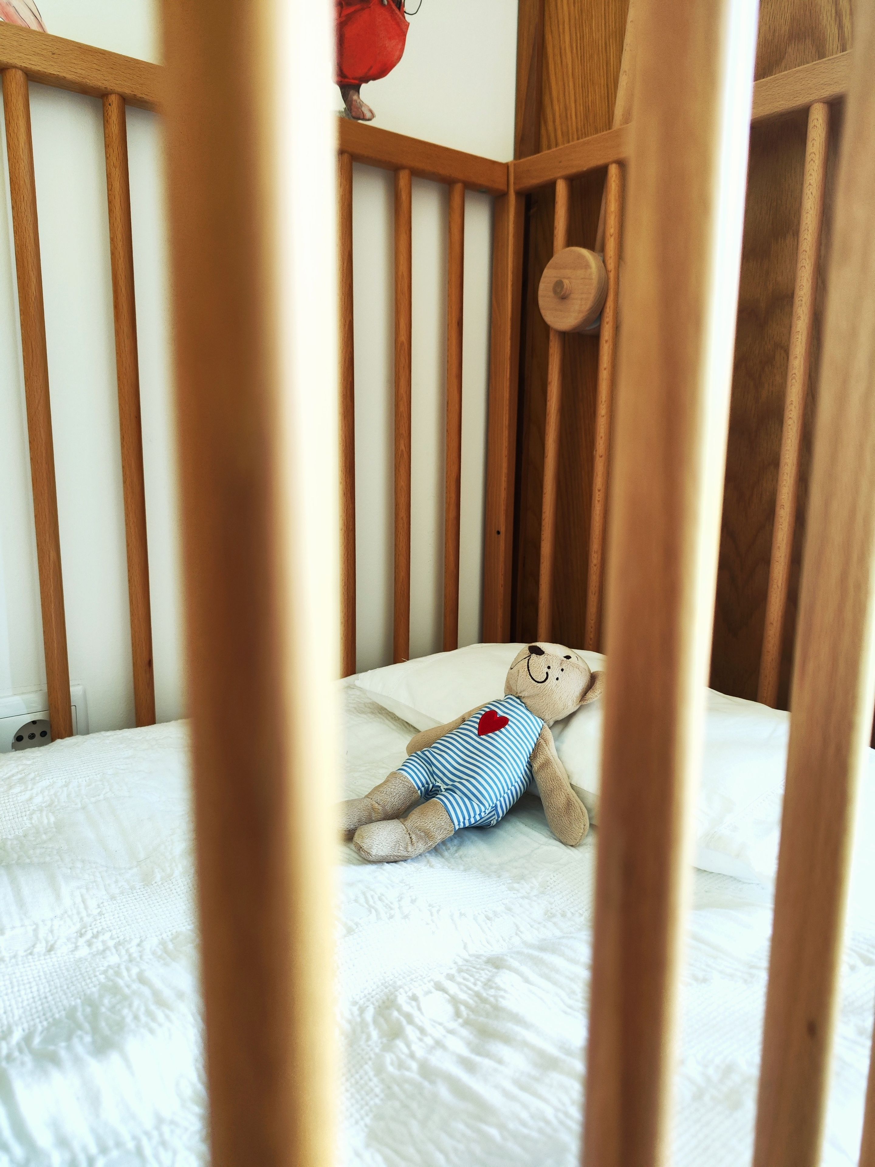 Ein Babybett mit Teddybär auf einer weißen Matratze.