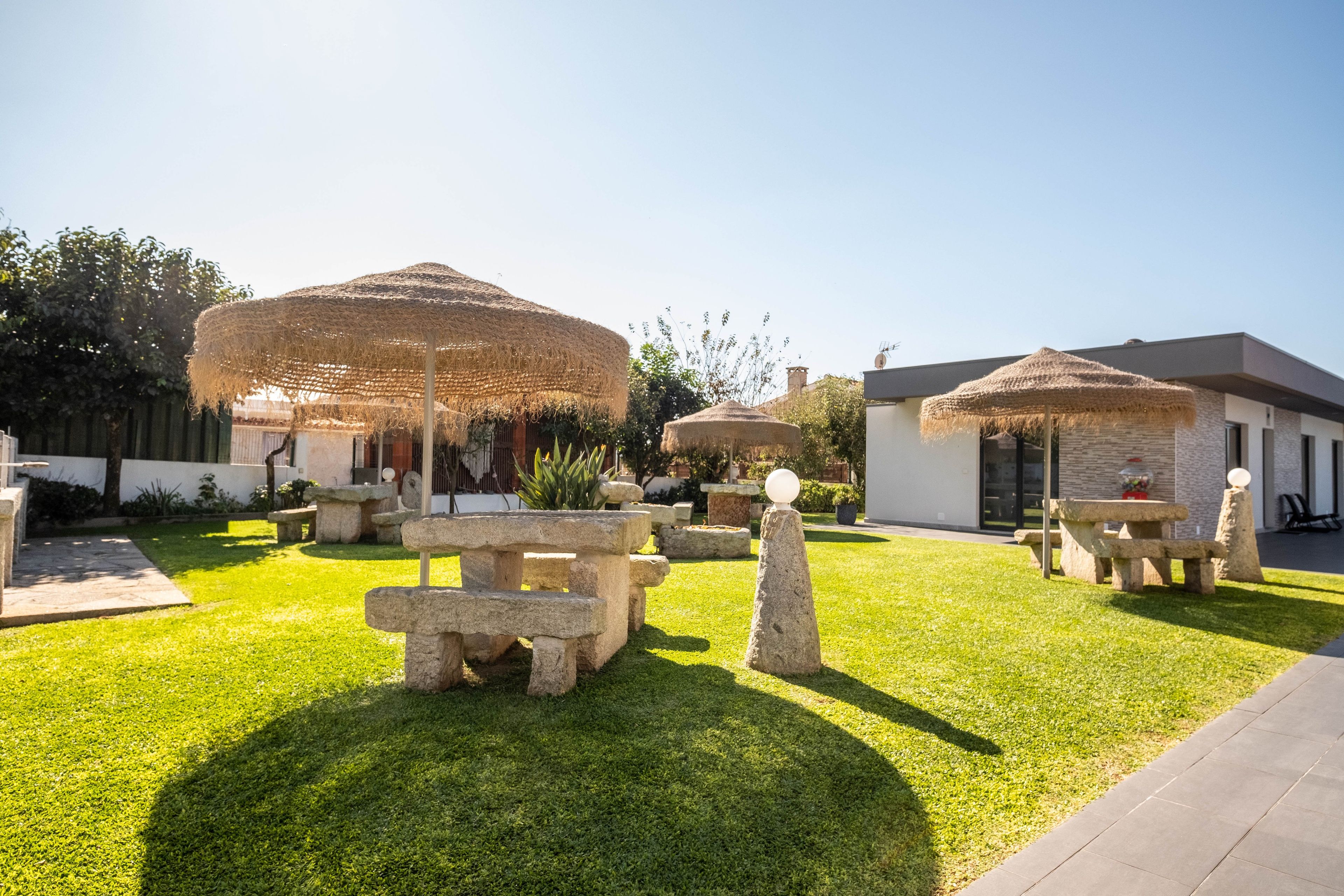 A well-maintained outdoor area with stone tables and thatched umbrellas, suggesting a casual dining or relaxation space.
