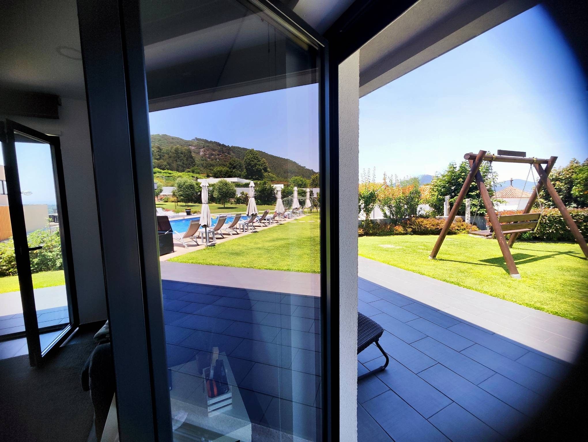 Un área exterior moderna con piscina, sillas de descanso y un columpio.