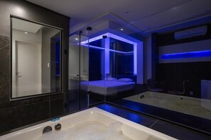 A modern bathroom with a large mirror, a bathtub, and a separate shower area.