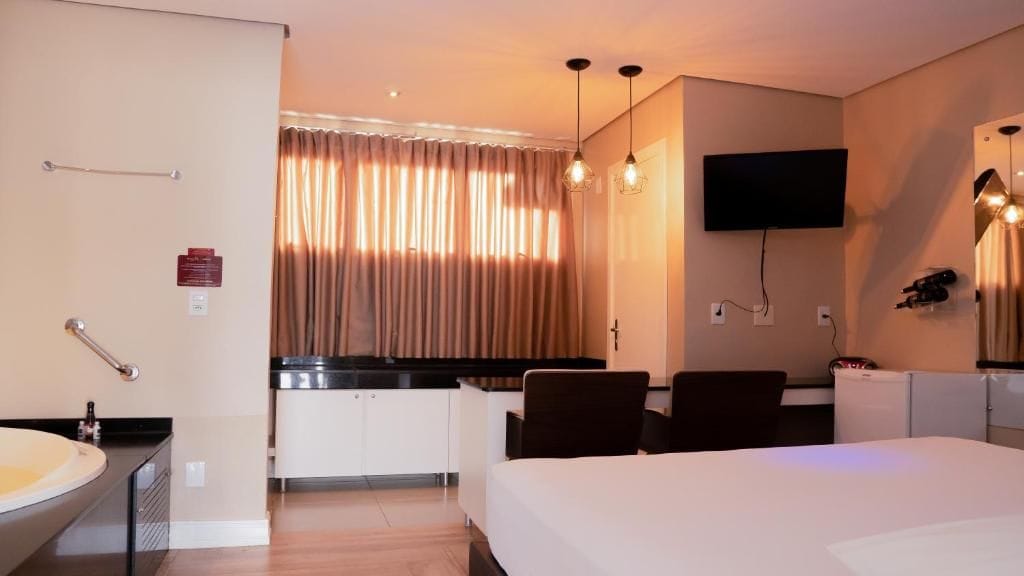 A hotel room with a bed, a desk, a television, and a bathroom.