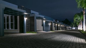 A nighttime view of a hotel corridor with multiple doors, each marked with a number.