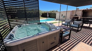 A hot tub with a built-in seating area, a pool, and outdoor furniture. - New Listing (Velaux)