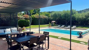 A covered outdoor area with a pool, lounge chairs, and a table with chairs. - New Listing (Velaux)