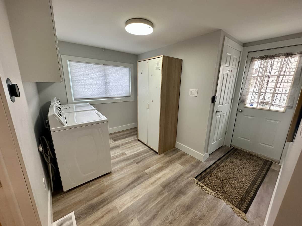 A laundry room with a washing machine, a drying rack, and a wardrobe.