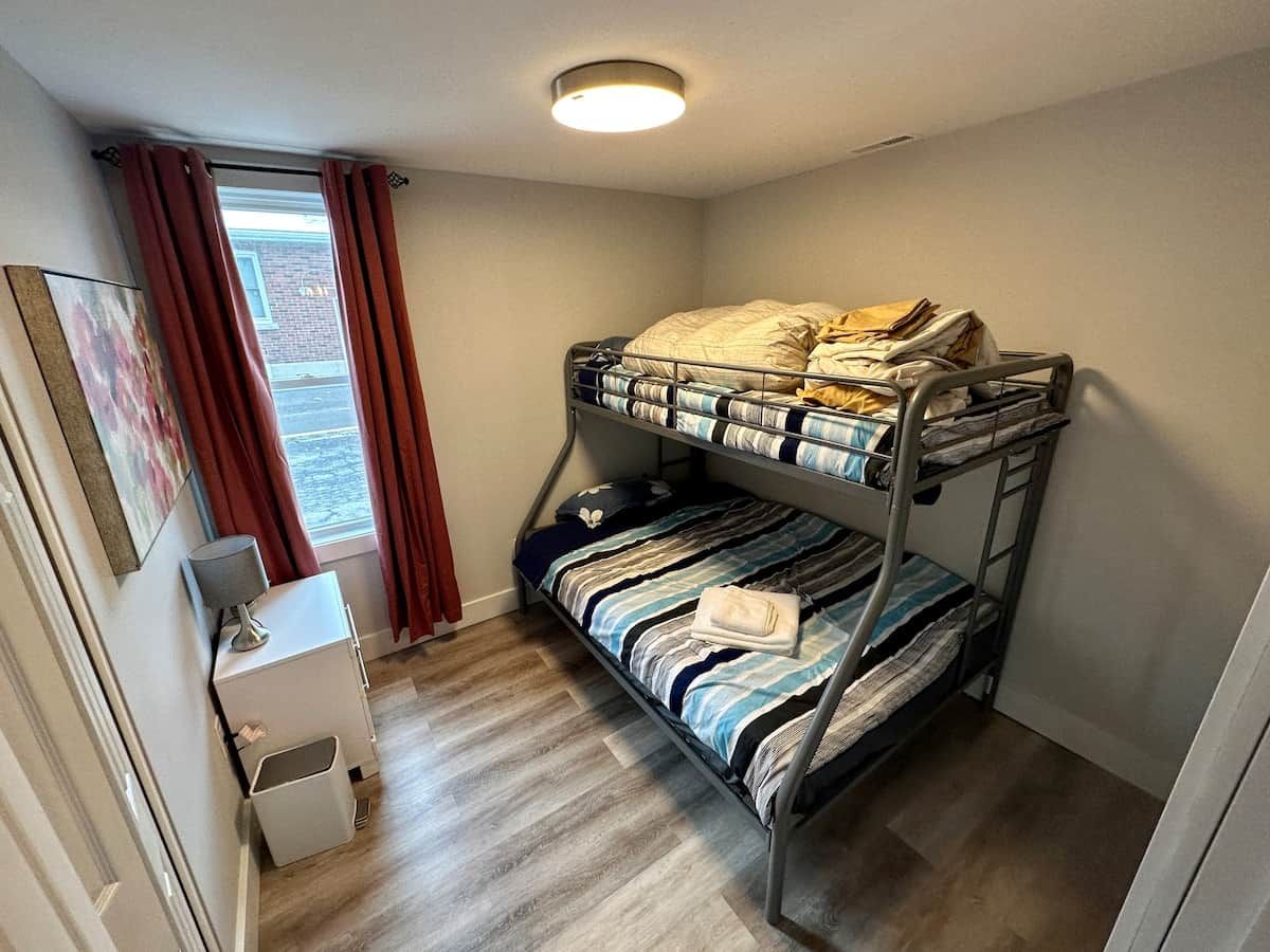 A bunk bed room with a desk and a window.