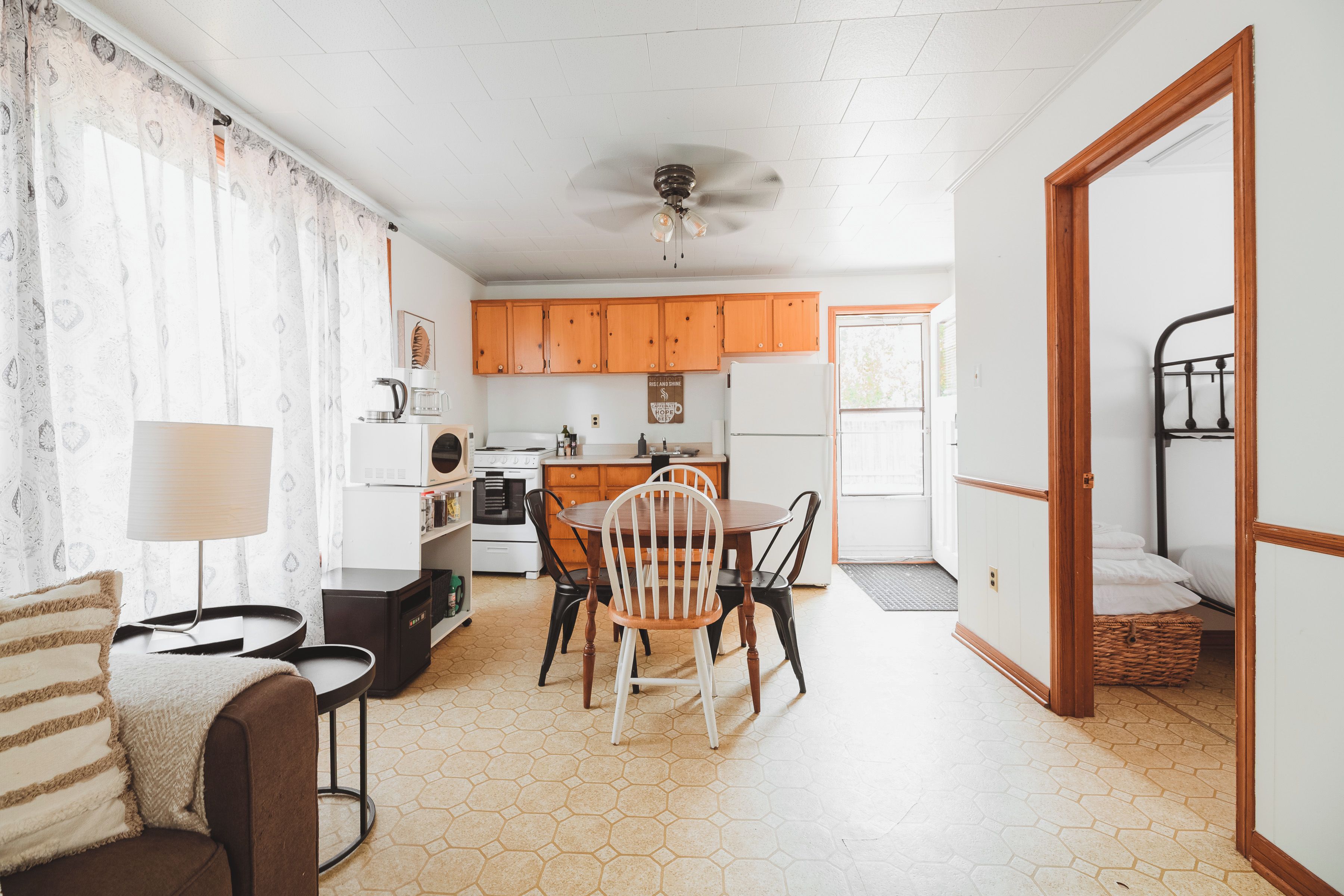 A compact living space with a dining area, kitchen, and a bedroom with a bed and a small table.