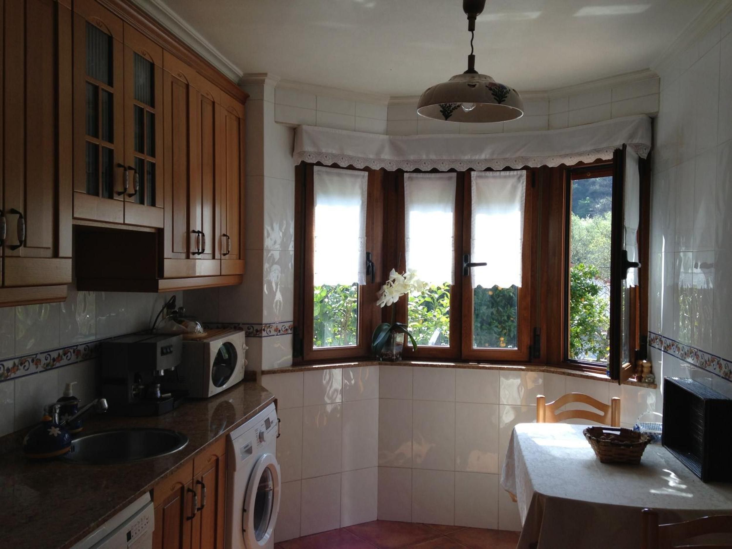Une cuisine avec des meubles en bois, un lave-linge, un four à micro-ondes et un coin repas comprenant une table et des chaises.