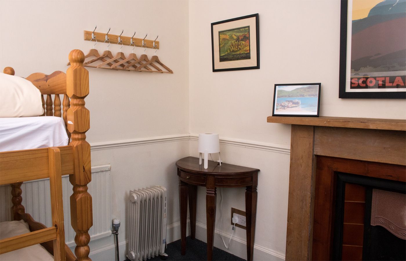 Traditional Highland warmth with practical touches. This cosy bedroom features pine bunk accommodation, a classic wooden fireplace surround, and vintage travel prints celebrating the scenic railway heritage.