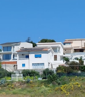 Un immeuble résidentiel moderne à plusieurs étages, doté de balcons, de grandes fenêtres et d’un toit plat.