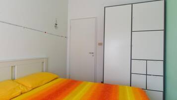 A bedroom with a bed, a wardrobe, and a door.