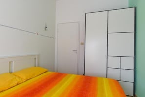 Une chambre à coucher avec un lit, une armoire et une porte.