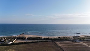 Un paysage côtier avec une plage, un promontoire rocheux et un ciel dégagé.
