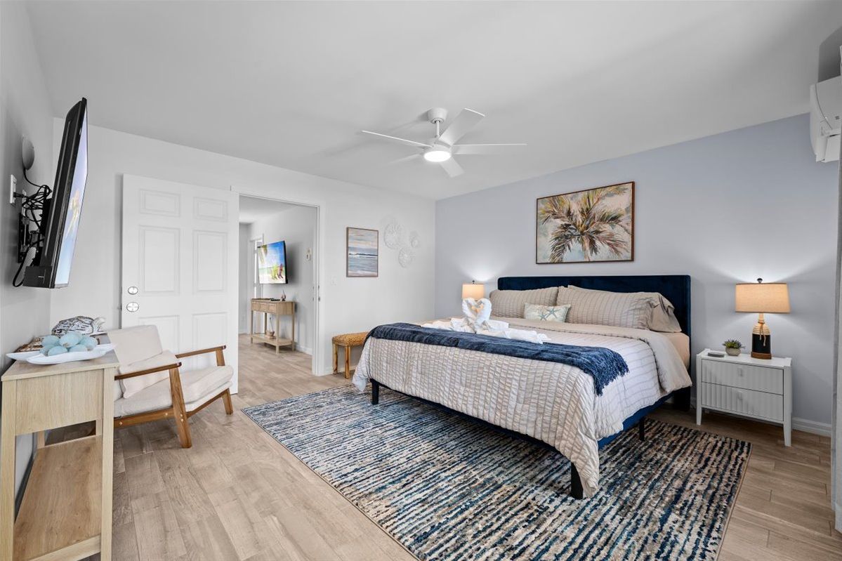 Spacious king bedroom with coastal style, TV, seating, and warm natural light